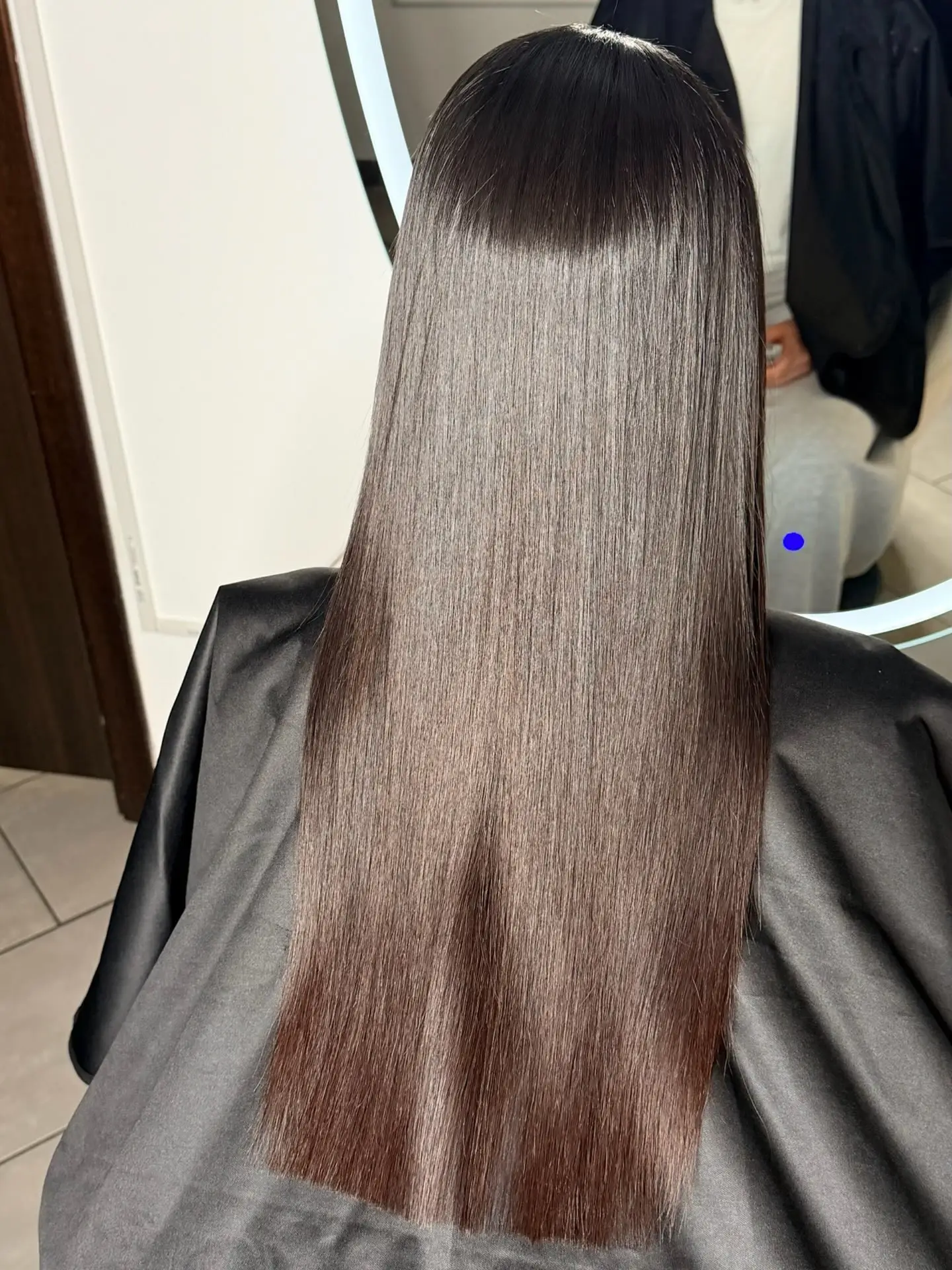 Capelli castano scuro lunghi e lisci, di spalle davanti allo specchio