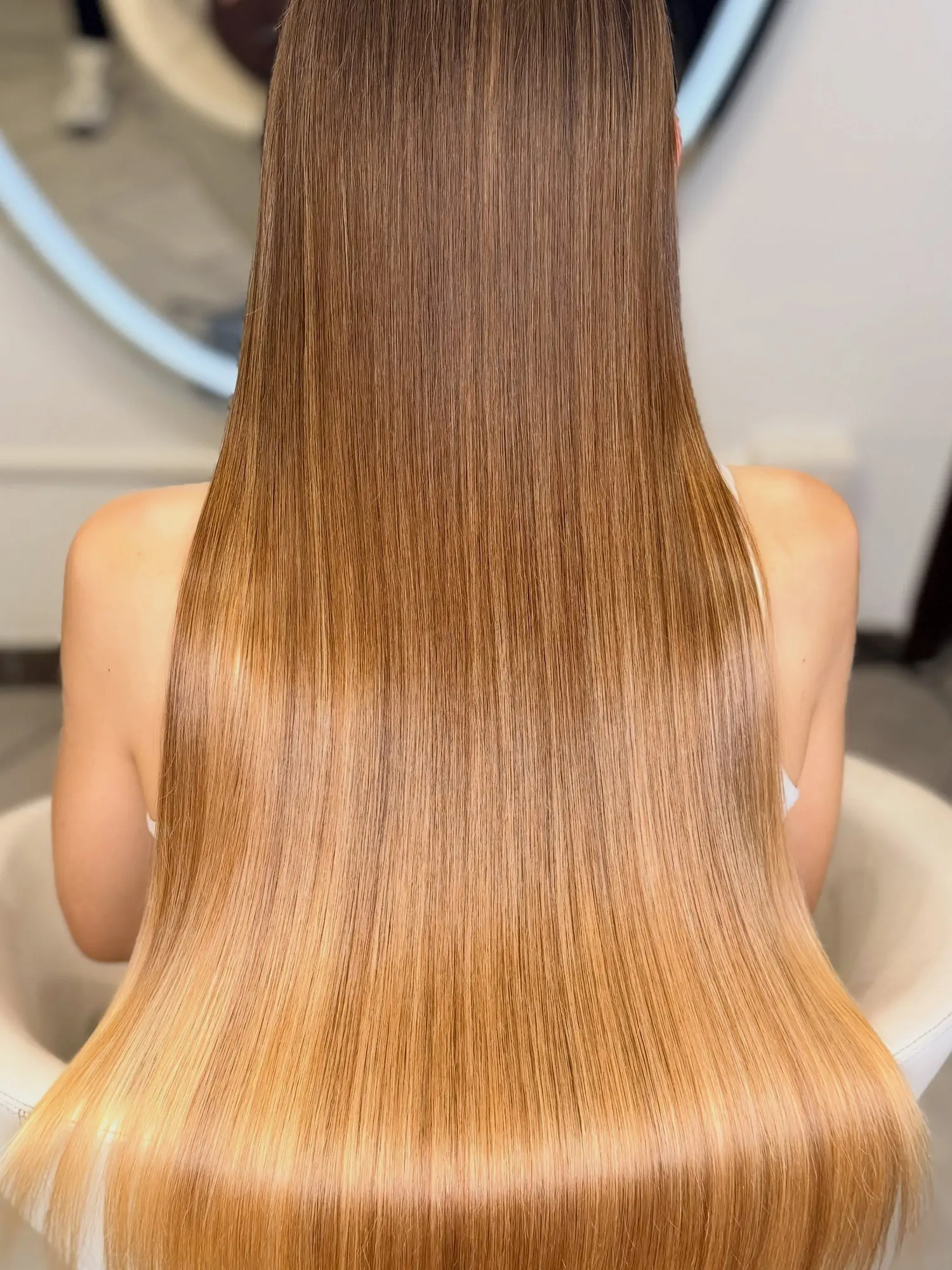 Capelli ramati lunghi e lucidi davanti allo specchio del salone